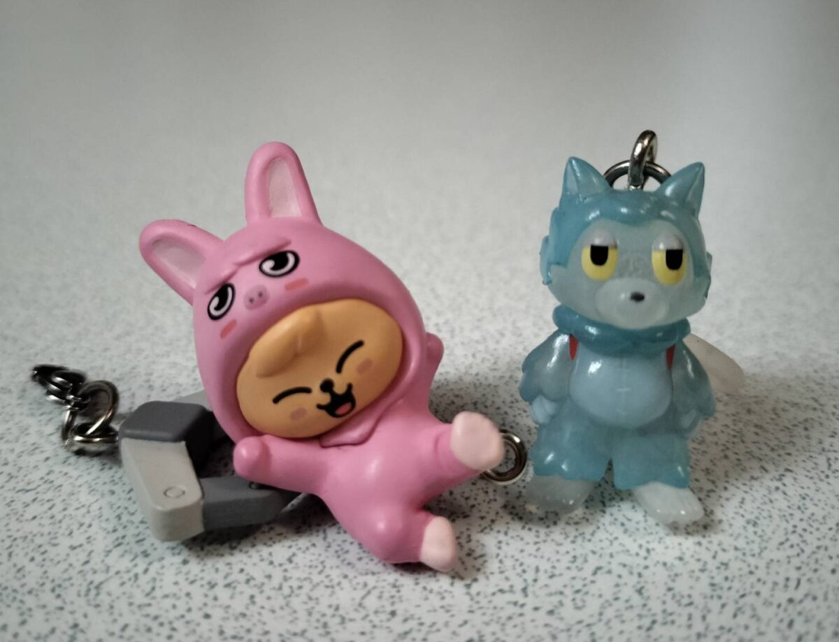 カプセルトイで手に入れたStray KidsのSKZOO(ピンクのうさぎ)と、あらいきりこさんのキャラクター(青いおおかみくん)のめじるしアクセサリー。