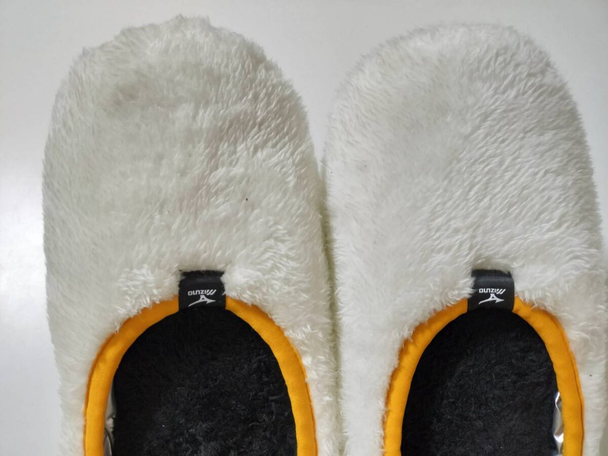 ふわふわの白いファー素材のアップ画像。履き口に黄色のパイピング（縁取り）があるデザイン。